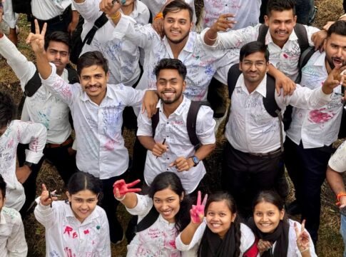 A vibrant group of college students celebrating outdoors with cheerful expressions and white shirts signed with colorful inks.