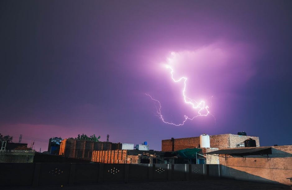 Punjab Power Strike: Services Disrupted Amidst Union Agitation Withdrawal A vivid lightning bolt illuminates the night sky over Faisalabad, Pakistan, casting dramatic shadows on city rooftops.