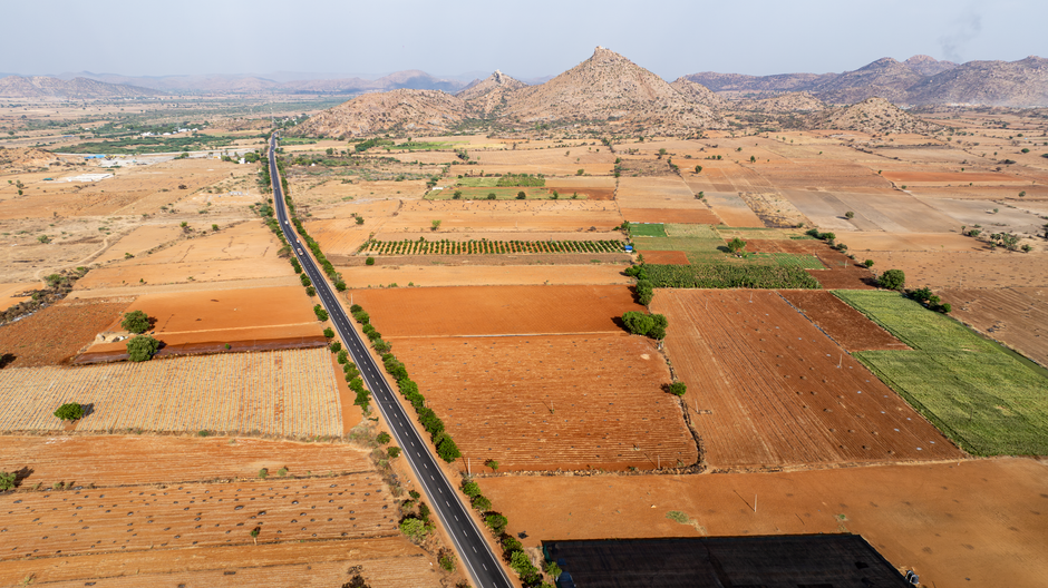 Karnataka Farmers Allege Real Estate Conspiracy Behind Flawed PIL on Bidadi Township Project Aerial perspective of agricultural fields and a road intersecting the farmland landscape.