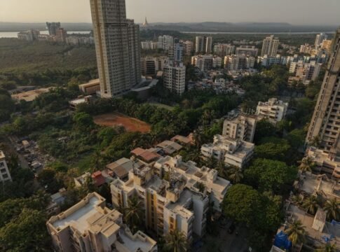 Aerial shot of dense residential skyscrapers in Mumbai, surrounded by green areas at dusk. Aerial shot of dense residential skyscrapers in Mumbai, surrounded by green areas at dusk.