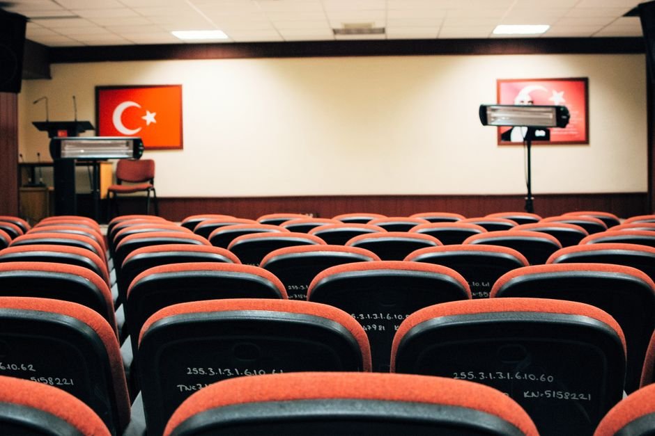 Jammu and Kashmir Party Plans Delhi Protest for Statehood Restoration An empty conference room featuring red seats, a stage, and Turkish flags, ready for a meeting or presentation.