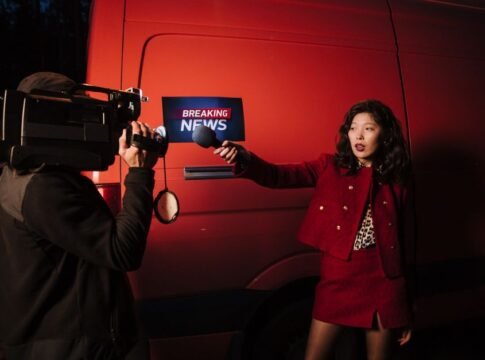 Asian female reporter with cameraman conducting a nighttime news broadcast beside a news van. Asian female reporter with cameraman conducting a nighttime news broadcast beside a news van.