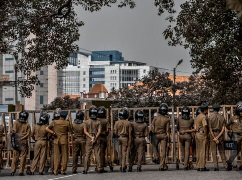 Back view of police officers in uniform standing on a city street surrounded by buildings and trees. Back view of police officers in uniform standing on a city street surrounded by buildings and trees.