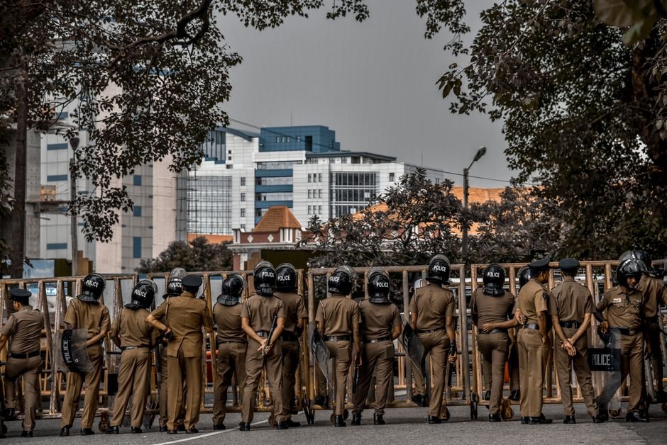 Mysuru Regional Commissioner Emphasizes Mock Tests for Police Aspirants Back view of police officers in uniform standing on a city street surrounded by buildings and trees.