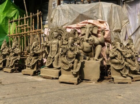 Clay statues of Lord Ganesh lined up outdoors in traditional workshop.