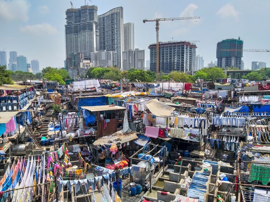 Mumbai Swelters as Monsoon Takes a Break, Dry Weather Expected This Week Colorful laundry drying at Mumbai Dhobi Ghat with city skyline in background.