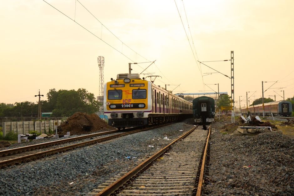 Central Railway Extends Train Cancellations on Mumbai-Pune Route Amid Ongoing Landslide Restoration Commuter train travels through a railway station under the warm sun.