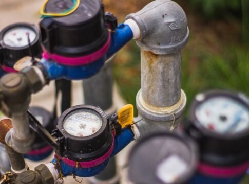 Detailed image of industrial water pressure gauges and pipes in an outdoor setting.