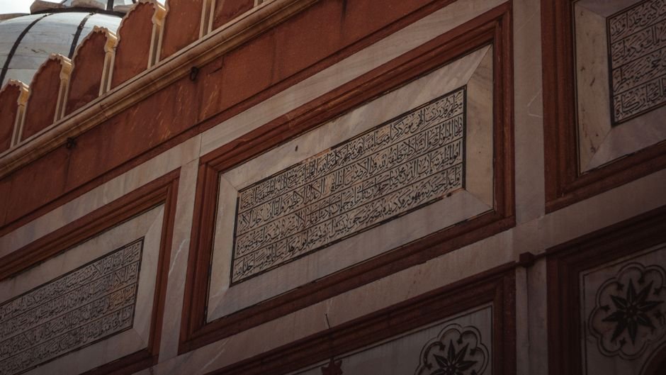 Mughal Era Calligraphy Flourished in Kashmir, Leaving Enduring Artistic Legacy Detailed view of Arabic inscriptions on a historic wall, showcasing intricate architecture.