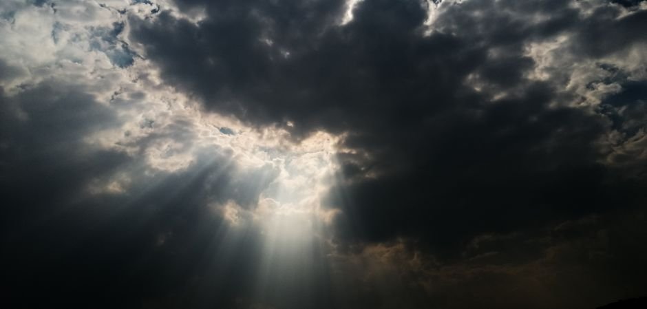 Jammu and Kashmir: Cloudbursts Trigger Flash Floods in Anantnag’s Shangus and Pahalgam Dramatic sky with sun rays piercing through dark clouds, creating a celestial atmosphere.