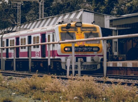 Front view of an Indian train at a railway station platform surrounded by greenery and infrastructure. Front view of an Indian train at a railway station platform surrounded by greenery and infrastructure.
