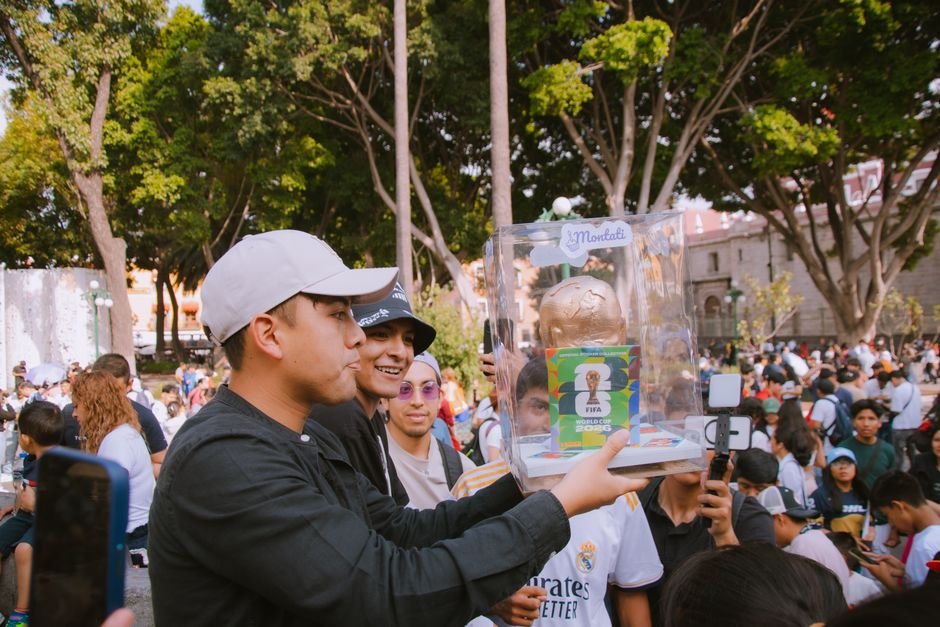 Bengaluru’s Nightlife Thrives as FIFA World Cup Captivates Fans Amidst Cricket Dominance Group of people celebrating with a FIFA World Cup trophy replica in a vibrant outdoor setting.