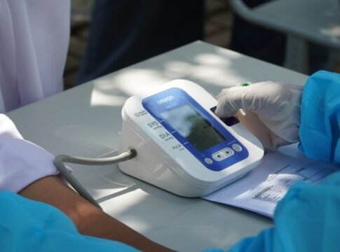 Healthcare worker checking patient's blood pressure with a digital device outdoors. Healthcare worker checking patient's blood pressure with a digital device outdoors.