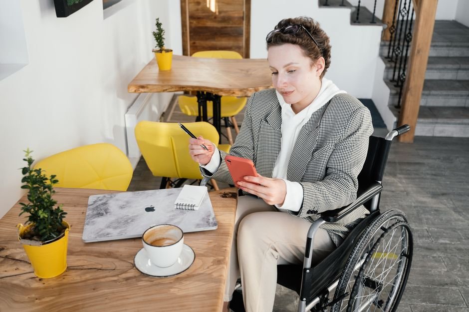 Andhra Pradesh College Organizes Workshop on Digital Accessibility for Visually Impaired High angle of focused female in wheelchair browsing cellphone at table with netbook and cup of latte