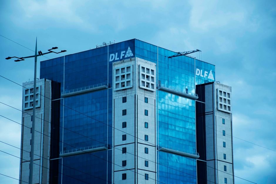 Gurugram Global City Project to Benefit from Enhanced Multi-Highway Connectivity High-rise commercial building DLF Square in Gurugram with glass facade under cloudy sky.