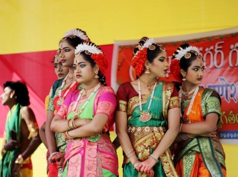 Indian dancers in traditional attire performing at a cultural festival outdoors.