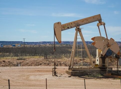 Industrial oil pumpjack in a desert setting under a clear blue sky, illustrating oil extraction technology.