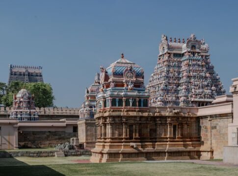 Intricate temple architecture under a clear blue sky in Tamil Nadu, showcasing vibrant sculptures and traditional design.