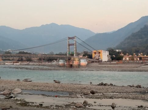 Laxman Jhula bridge spanning Ganges River in Rishikesh with mountainous backdrop.