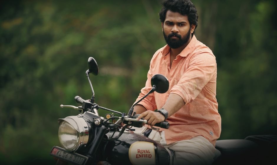 Kerala CM V.D. Satheesan Offers Prayers at Kollur Mookambika Temple Man in pink shirt riding a Royal Enfield motorcycle outdoors, showcasing adventure and freedom.