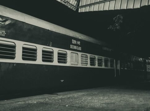 Night photo of a second class train parked outdoors under a station roof.