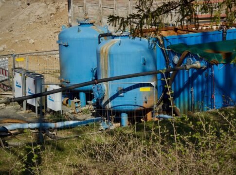 Outdoor industrial water filtration plant with large blue tanks under sunlight. Outdoor industrial water filtration plant with large blue tanks under sunlight.