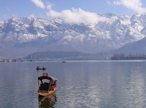 Peaceful view of Dal Lake in Srinagar surrounded by snowcapped Himalayas, featuring traditional boats. Peaceful view of Dal Lake in Srinagar surrounded by snowcapped Himalayas, featuring traditional boats.