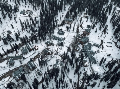 Snow-covered aerial view of Gulmarg, showcasing buildings and pine trees in winter. Snow-covered aerial view of Gulmarg, showcasing buildings and pine trees in winter.