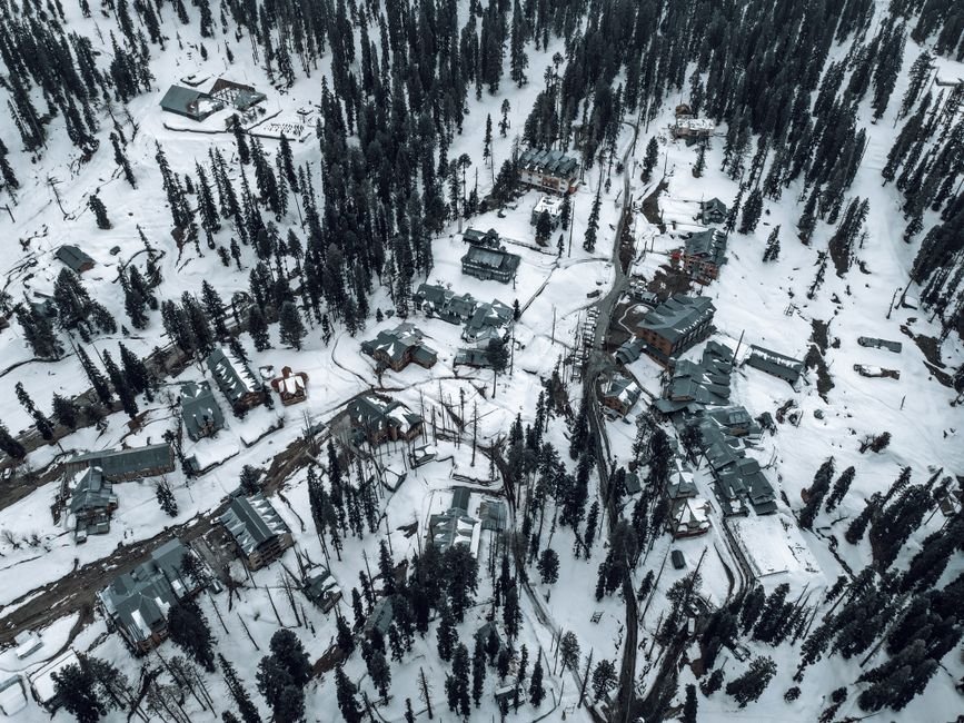 Jammu and Kashmir: Gulmarg Introduces Trial Odd-Even Vehicle Rule to Ease Traffic Congestion Snow-covered aerial view of Gulmarg, showcasing buildings and pine trees in winter.
