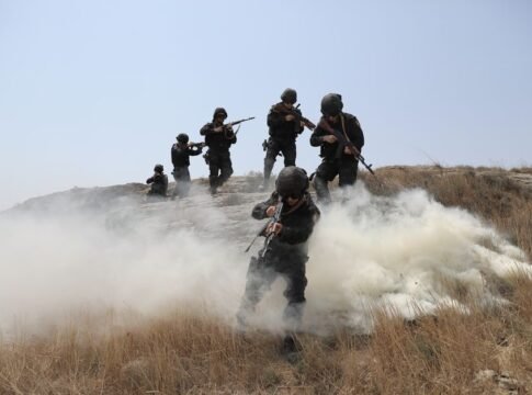 Soldiers advancing through a field with smoke during a training exercise. Soldiers advancing through a field with smoke during a training exercise.