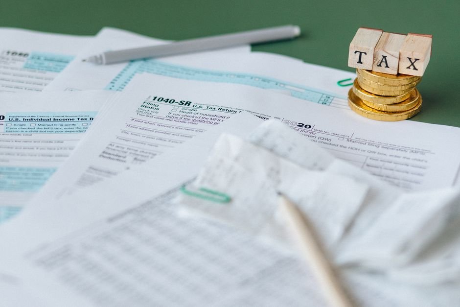 Mumbai ITAT Rules Redeveloped Flats Qualify for Long-Term Capital Gains Tax Benefits Stack of tax forms and coins with a 'TAX' stamp, symbolizing finance and accounting.