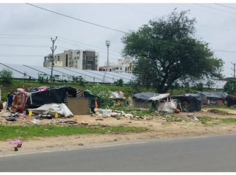 Street scene showing makeshift homes near solar panels in Vadodara, India.