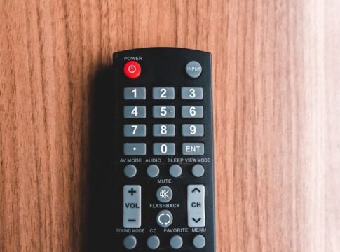 Top view of plastic remote control with rows of buttons representing power and mute symbols on brown background Top view of plastic remote control with rows of buttons representing power and mute symbols on brown background