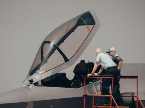 Two men inspecting military aircraft cockpit on a clear day. Two men inspecting military aircraft cockpit on a clear day.