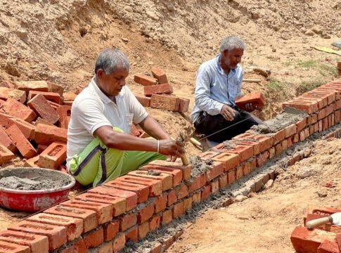 Two men laying bricks at a construction site in Rasulpur, India.