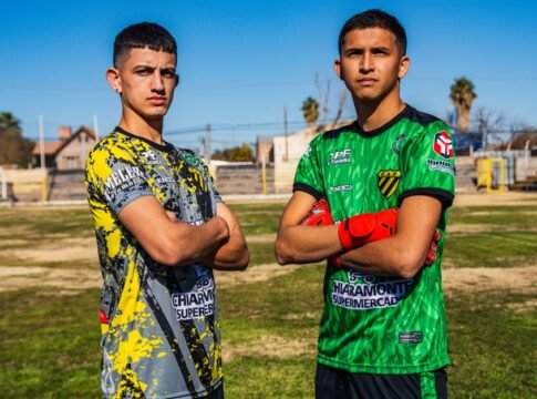 Two young men proudly posing on a soccer field, wearing team jerseys. Two young men proudly posing on a soccer field, wearing team jerseys.