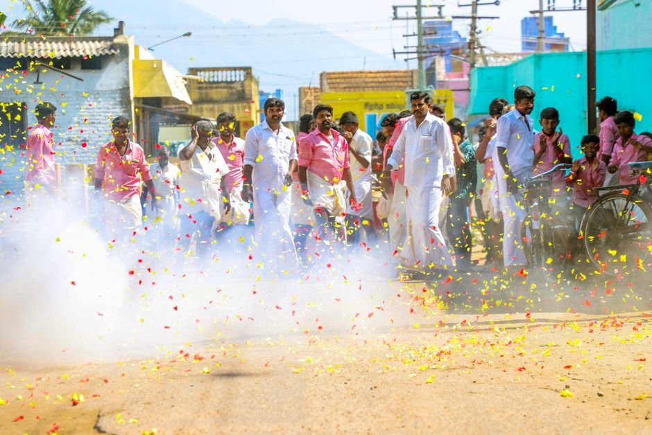 Tamil Nadu: Ex-Minister Vaigaichelvan Quits AIADMK, Cites Leadership Issues Vibrant street celebration with people amidst firecrackers and colorful confetti during the day.
