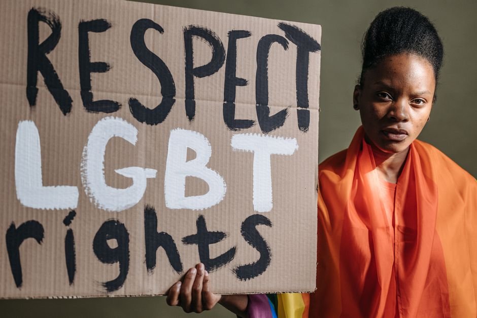 Karnataka Gender Minority Groups Urge Welfare Board, Ordinance Against Transgender Persons Act Woman holding a sign advocating for LGBT rights, highlighting social justice.
