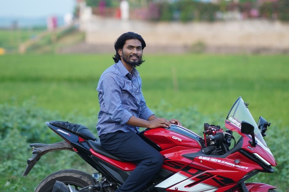 Young man on a stylish red motorcycle enjoying a ride through the scenic countryside.