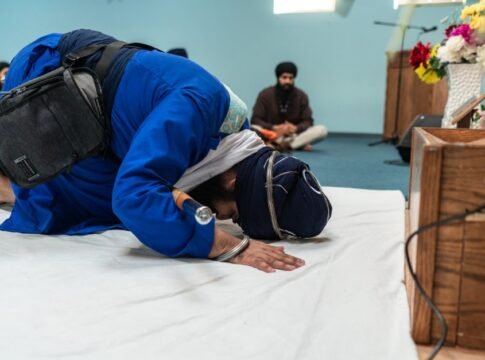 A Sikh man prostrating in prayer inside a gurdwara, emphasizing devotion and spirituality.