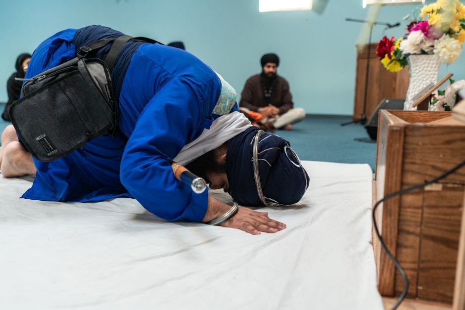 Punjab: SGPC Issues Legal Notice to GTC Over Unauthorized Gurbani Telecast A Sikh man prostrating in prayer inside a gurdwara, emphasizing devotion and spirituality.