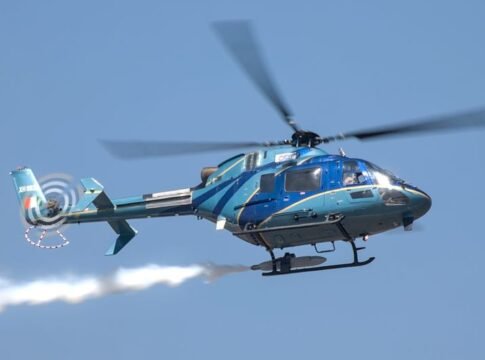 A blue military helicopter showcasing aerobatic maneuvers at an air show in Bengaluru, India. A blue military helicopter showcasing aerobatic maneuvers at an air show in Bengaluru, India.