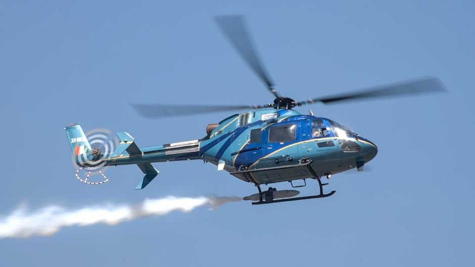 Bengaluru to Host Aero India 2027 in February A blue military helicopter showcasing aerobatic maneuvers at an air show in Bengaluru, India.