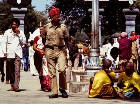 A bustling street scene in India featuring a diverse crowd and a policeman walking amidst people. A bustling street scene in India featuring a diverse crowd and a policeman walking amidst people.
