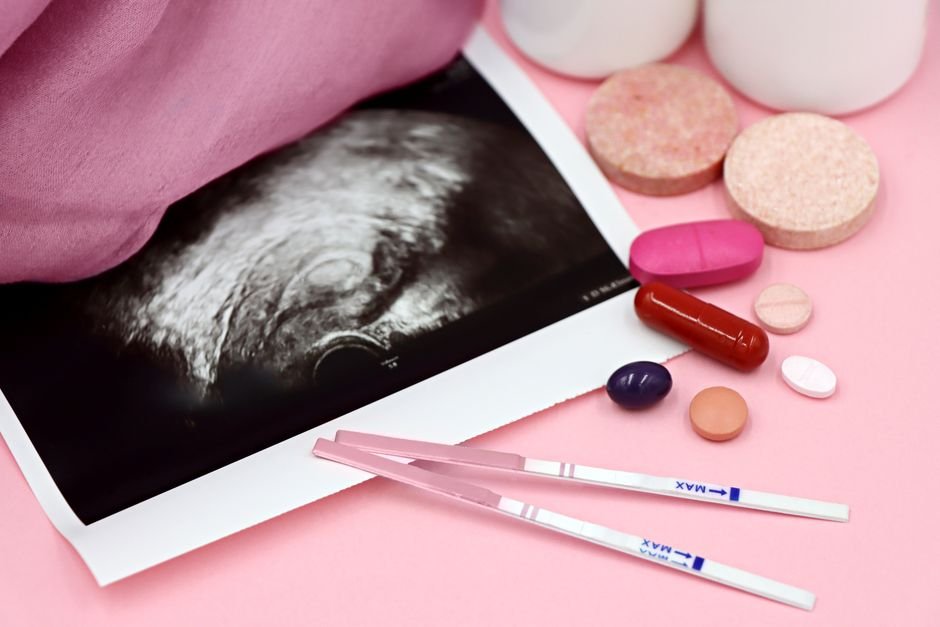 Jammu and Kashmir Faces Declining Fertility Amid Rising Premature Ovarian Insufficiency A closeup of pregnancy tests and an ultrasound with supplements on a pink background.