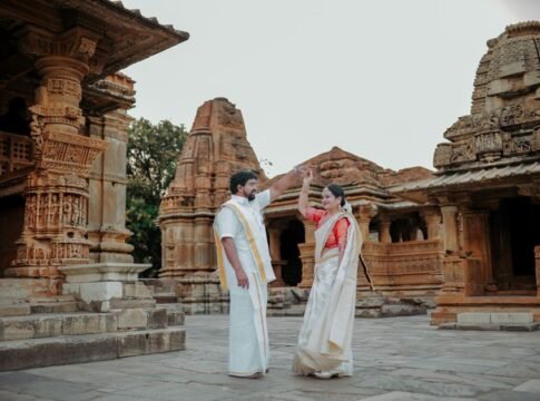 A couple in traditional attire poses charmingly at an ancient temple, symbolizing cultural heritage.