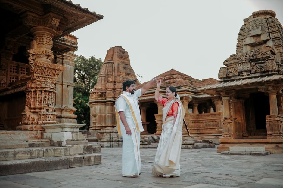 A couple in traditional attire poses charmingly at an ancient temple, symbolizing cultural heritage.