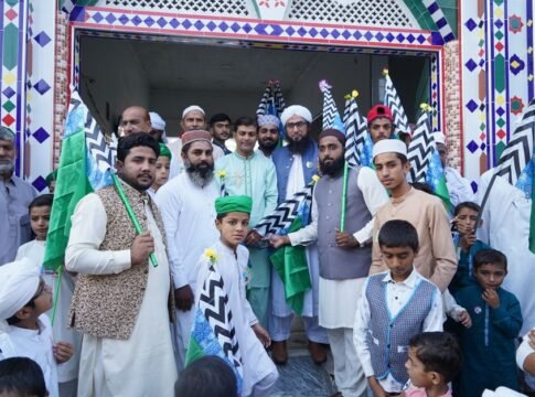 A diverse group of men and boys in traditional attire holding flags at a ceremonial event.