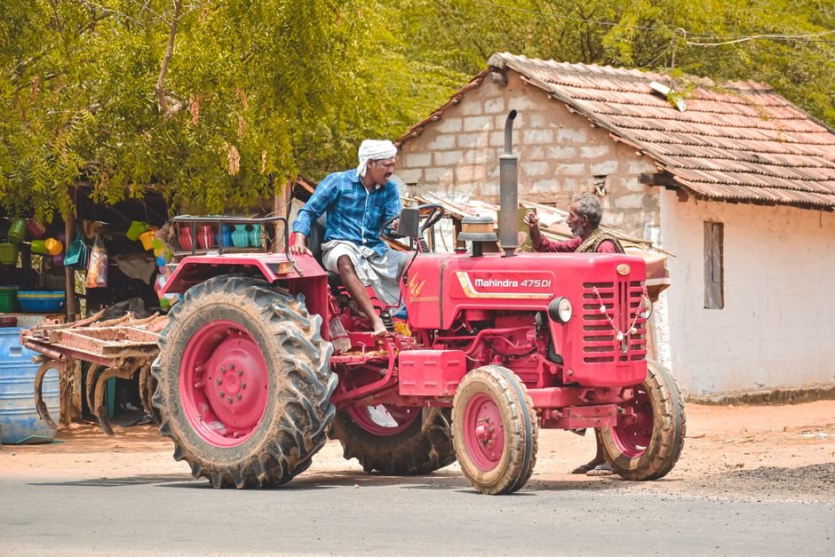 Tamil Nadu Farmers Urged to Use PPFM Spray to Combat Drought Conditions A farmer driving a red Mahindra tractor in Aranthangi, Tamil Nadu, India, showcasing rural life.