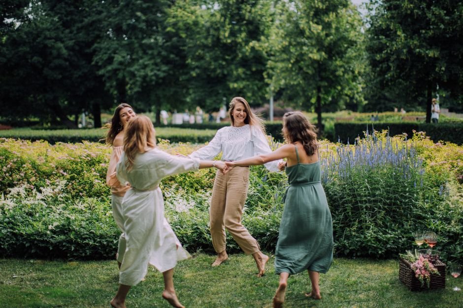 India’s Electronics Sector Sees Women Take the Lead on Factory Floors A group of women joyfully dancing in a park on a summer day, exuding happiness.